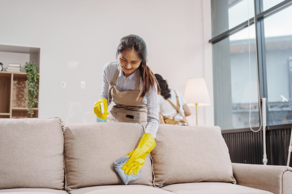 Two women contractors working as housekeepers in an office, wiping glass, sweeping floors, mopping