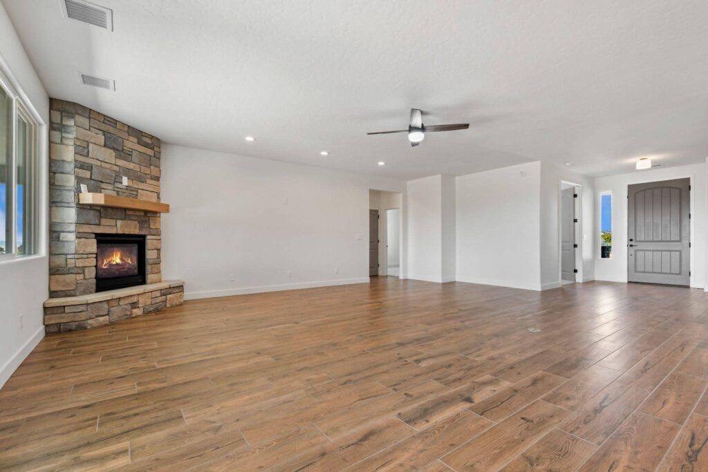 A spacious empty living room featuring a central fireplace and neutral-colored walls
